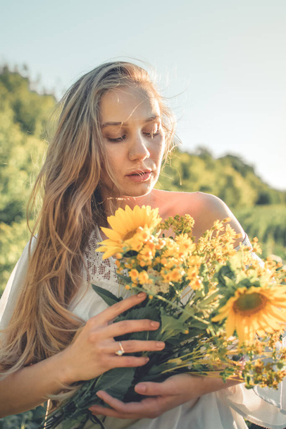 Hoe te oogsten en te drogen kruiden. Traditionele geneeskrachtige planten. Vrouw plukken bloem in de zomer veld met zonlicht straal. - Foto, afbeelding