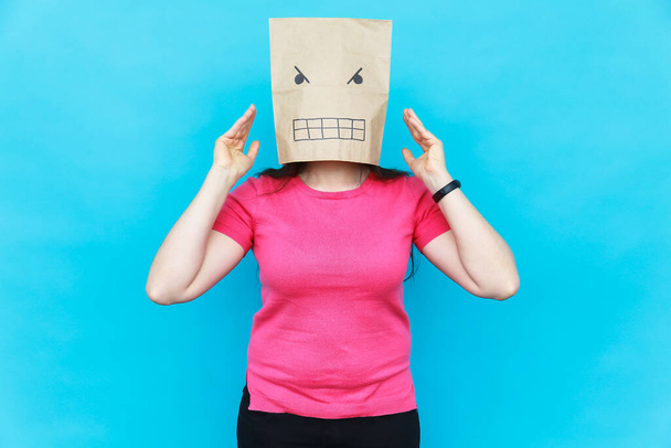 Een vrouw met een karton op haar hoofd met een boos gezicht. Emoties concept. - Foto, afbeelding