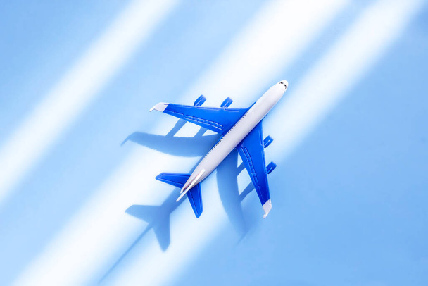 Модель плоскости на синем фоне с тенью. Миниатюрный игрушечный самолет. Вид сверху, плоский. Концепция путешествий и отдыха
. - Фото, изображение