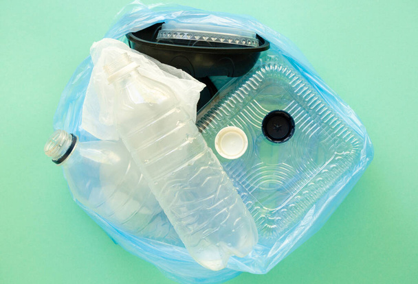 Plastic waste in trash bag on a mint background - Foto, afbeelding