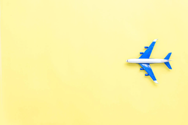Modelo plano sobre fondo de color pastel amarillo. Avión de juguete miniatura. Vista superior, plano, espacio de copia. Concepto de viaje y vacaciones
. - Foto, imagen