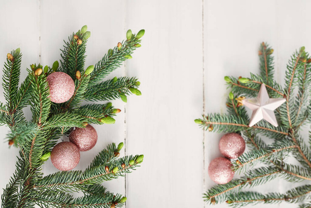 Christmas composition. Fir branches on wooden white background. Flat lay, top view, copy space. Christmas still life.Christmas frame made of fir branches and pink toys. Greeting card. Happy New Year - Photo, Image