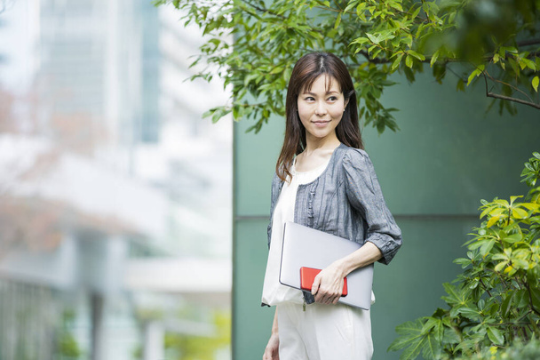 Asiática (japonesa) trabajadora de oficina que trabaja al aire libre con una computadora portátil
 - Foto, Imagen
