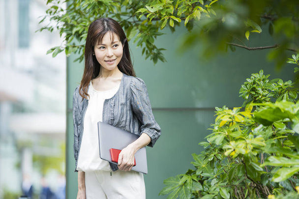 Aziatisch (Japans) vrouw kantoormedewerker werken buiten met een laptop - Foto, afbeelding