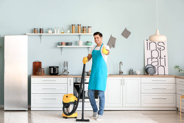 Young man with vacuum cleaner in kitchen - Photo, Image