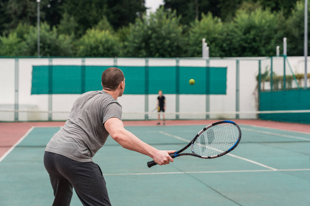 El hombre está jugando al tenis con un cordón azul. Vista lateral trasera
 - Foto, Imagen