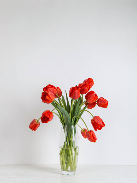 Red tulips in vase on the table, on a white background. Postcard blank. - Фото, изображение