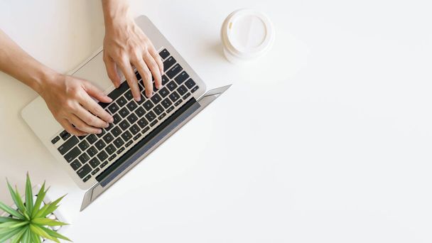 Espacio de trabajo con las manos escribiendo en el ordenador portátil. Piso tendido, vista superior - Foto, Imagen