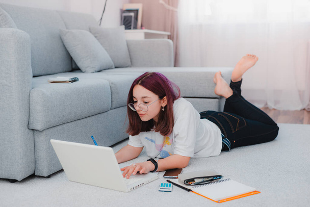 młoda dziewczyna nastoletnia uczennica leżąca piętro salon sofa student studiuje w domu pracując z laptopem odrabiając lekcje. Koncepcja kształcenia na odległość podczas kwarantanny koronawirusu covid-19 - Zdjęcie, obraz