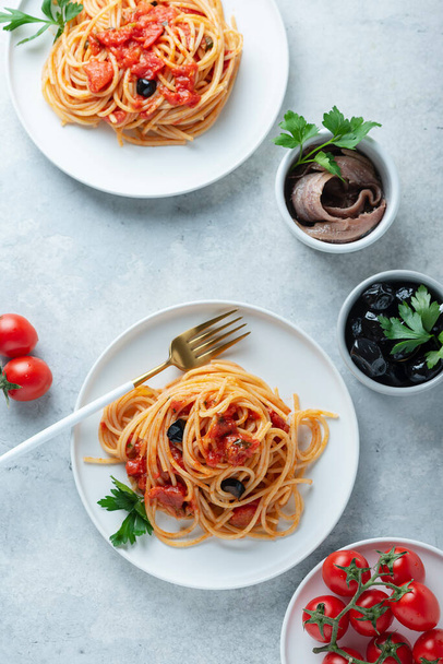 Traditional italian pasta with tomato, olives, capers, anchovies and parsley, top view image - Fotografie, Obrázek
