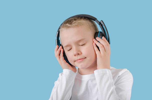 Young child keep your hands on the headphones and enjoying listening to music. Teen boy with headphones. - Photo, Image