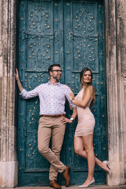 stylish guy and girl posing near turquoise door. ancient building and door. - Φωτογραφία, εικόνα