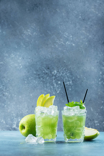 Green cocktail with ice and mint. Bar concept. Apple mojito with mint and ice on the blue background, selective focus image - Fotó, kép