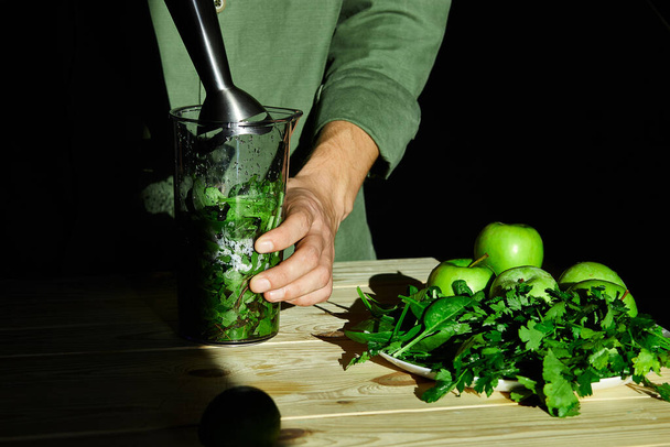 Process of preparing green detox smoothie with blender, young man hands cooking healthy smoothie with fresh fruits and greens spinach. Lifestyle detox concept. Vegan drinks. - Photo, Image