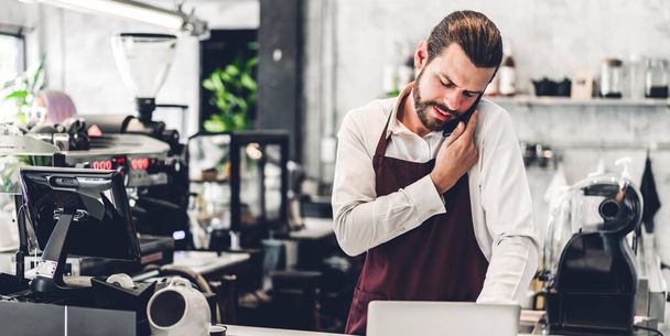 Portret van knappe barista man met baard kleine ondernemer werken en ontvangen bestelling van de klant achter de balie in een cafe - Foto, afbeelding