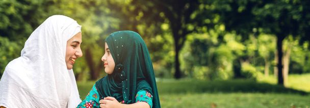 Portrait of happy religious enjoy happy love asian family arabic muslim mother and little muslim girls child with hijab dress smiling and having fun moments good time in summer park - Foto, Bild