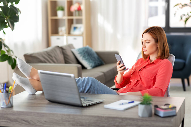 woman with smartphone and laptop at home office - Valokuva, kuva