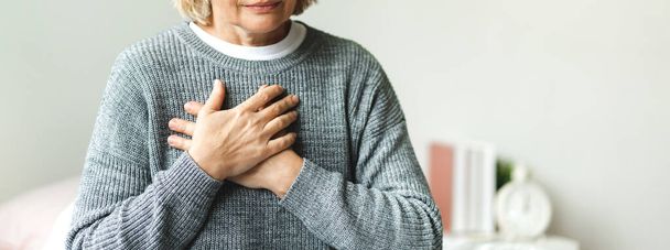 Senior adult elderly women sit on bed with chest pain suffering from heart attack in the bedroom.Healthcare and medical concept - Zdjęcie, obraz