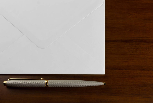 Elagant kynä vieressä valkoinen kirjekuori puinen pöytä
 - Valokuva, kuva