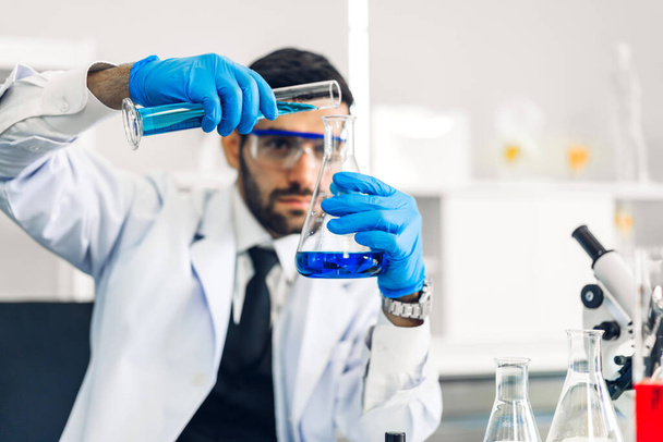 Profesyonel bilim adamı test tüpünde sıvı analiz ederken ve karıştırırken bir kimyasal deney yapıyor. Genç bilim adamı laboratuvarda cam üzerinde kimyasal örnekler arıyor. - Fotoğraf, Görsel