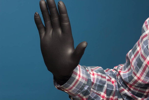 Hijyenik el koruması, ellerindeki teması kaybetmemek için siyah bir eldiven. El ve parmak izleri.. - Fotoğraf, Görsel
