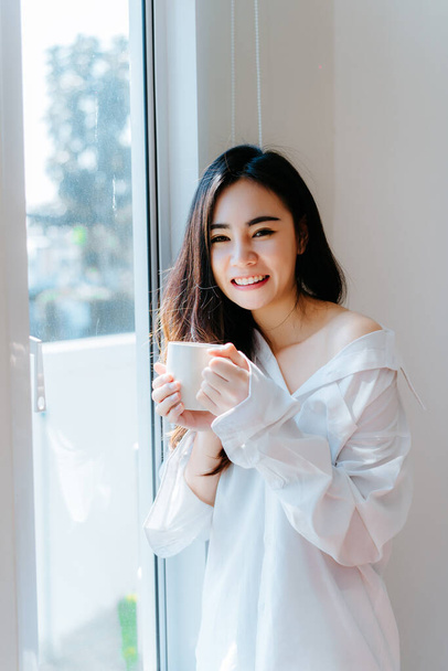 Asian woman drinking coffee in the morning breakfast in window bedroom fresh start the day happiness relax at home healthy lifestyle  - Foto, immagini
