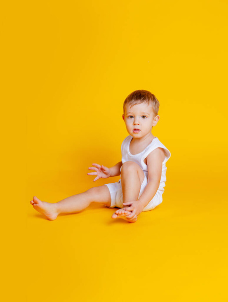 chłopiec w koszulce i bieliźnie siedzący na pomarańczowo-żółtym tle - Zdjęcie, obraz