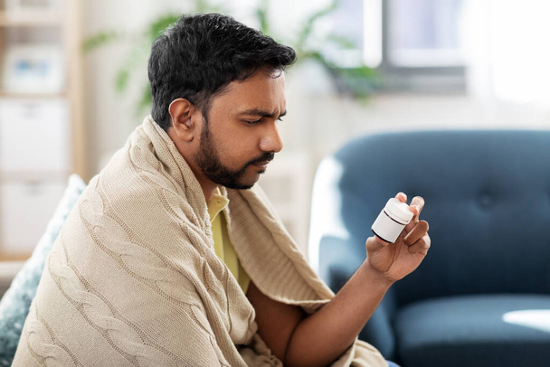 sad sick man in blanket with medicine at home - Foto, Imagen