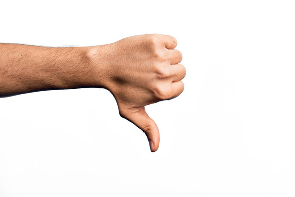Mano de joven caucásico mostrando dedos sobre fondo blanco aislado haciendo pulgares hacia abajo gesto de rechazo, desaprobación aversión y signo negativo - Foto, imagen