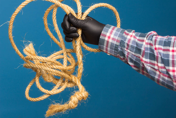 Yellow rope in the expert hand of an adult with protection. Thick rope to tie objects. - 写真・画像