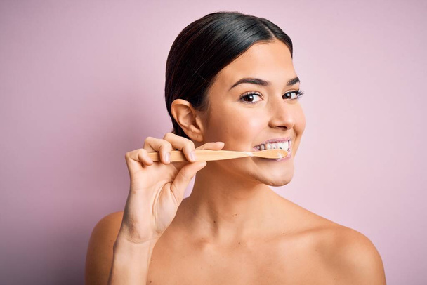 Young beautiful brunette woman brushing her teeth using tooth brush and oral paste, cleaning teeth and tongue as healthy health care morning routine - Photo, image