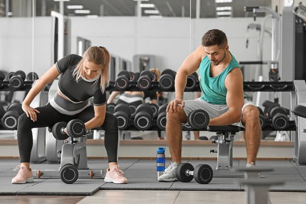 Sporty young couple training with dumbbells in gym - Foto, Imagem