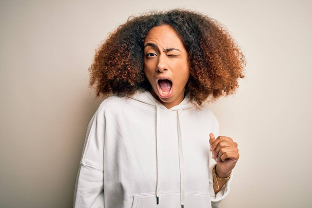 Young african american sportswoman with afro hair wearing sporty sweatshirt winking looking at the camera with sexy expression, cheerful and happy face. - Foto, Bild