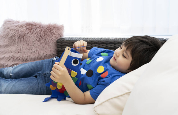High key happy kid stay at home lying on sofa playing Koinobori (Carp streamers),Child boy doing Japanese fish kite in sunny day summer, Distance education or Home schooling, Children's Day  - Foto, Bild