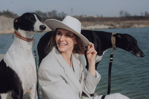 Een lachende vrouw met honden. Portret van een lachende vrouw met witte hoed en honden . - Foto, afbeelding