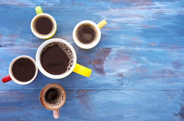 Kubki kawy na kolorowym drewnianym tle - Zdjęcie, obraz