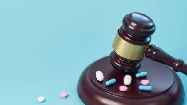 Wooden judge gavel with drugs on table. Space for text. Medical concept. on a blue background. expired drugs. fake market. - Photo, Image