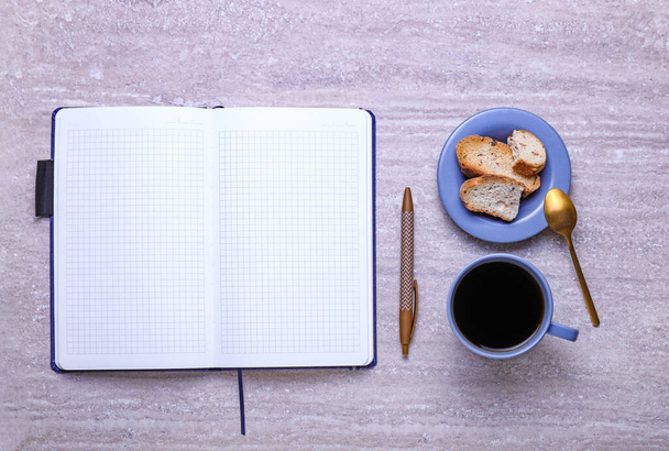 Xícara de café com biscoitos e caderno na mesa
 - Foto, Imagem