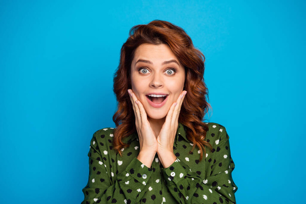 Closeup photo of crazy shocked lady open mouth see unbelievable sale prices advert arms on cheeks enjoy black friday wear green dotted shirt isolated blue color background - Foto, afbeelding