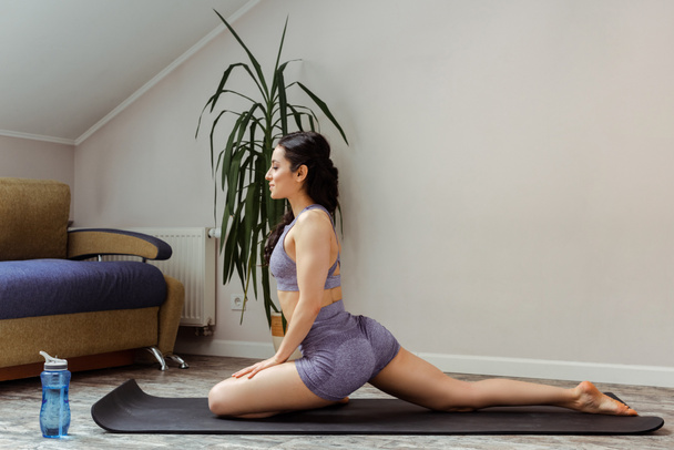 schönes Mädchen in Sportbekleidung praktiziert Yoga auf Matte zu Hause während der Selbstisolierung - Foto, Bild