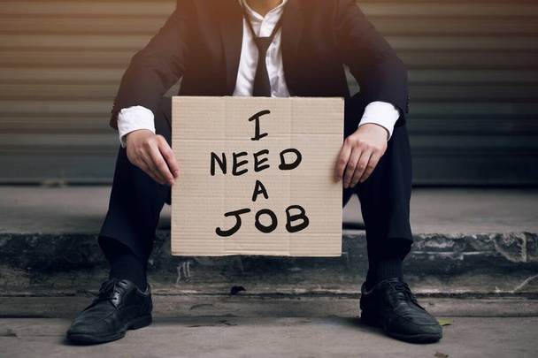 Un disoccupato in possesso di un cartello che scrive un messaggio dicendo che ha bisogno di un lavoro
 - Foto, immagini