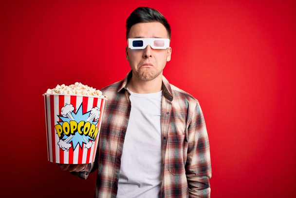 Nuori komea valkoihoinen mies yllään 3D-elokuvalasit ja syö popcornia masentunut ja huoli ahdistusta, itku vihainen ja peloissaan. Surullinen ilme
. - Valokuva, kuva
