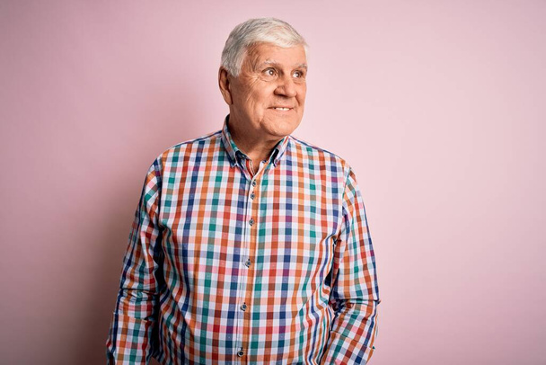 Senior handsome hoary man wearing casual colorful shirt over isolated pink background looking away to side with smile on face, natural expression. Laughing confident. - Zdjęcie, obraz