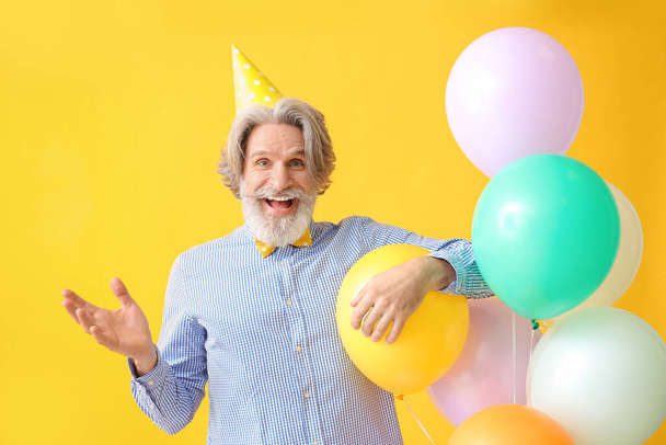 Senior férfi ünnepli születésnapját színes háttér - Fotó, kép