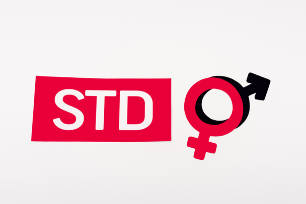bovenaanzicht van gendersymbolen bij papier met STD-letters geïsoleerd op wit  - Foto, afbeelding
