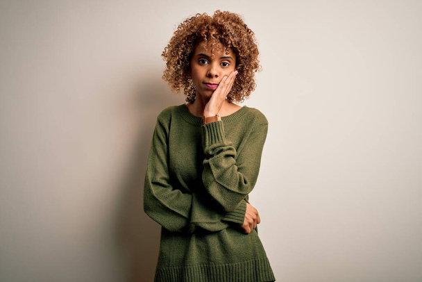 Beautiful african american woman with curly hair wearing casual sweater over white background thinking looking tired and bored with depression problems with crossed arms. - Foto, imagen