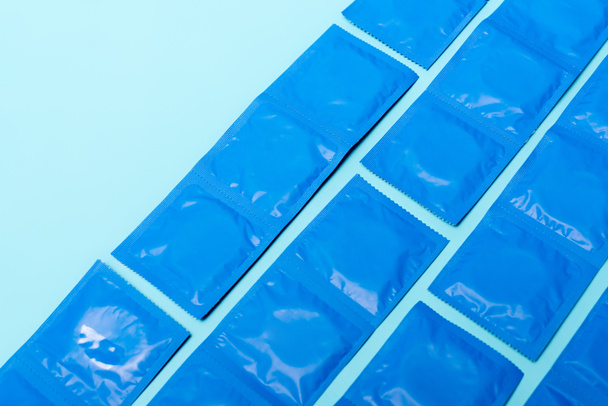 コピースペースのある青で隔離された避妊用のコンドーム付きのパック - 写真・画像