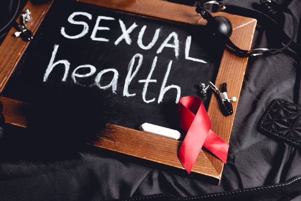 kréta szexuális egészség felirattal és szex játékok és piros szalag fekete selyem  - Fotó, kép