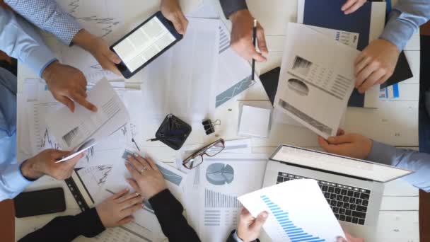 Top view male and female hands of business people planning strategy for corporate project in office. Business team checks financial graphs at desk. Colleagues sitting at table and examining documents - Кадри, відео