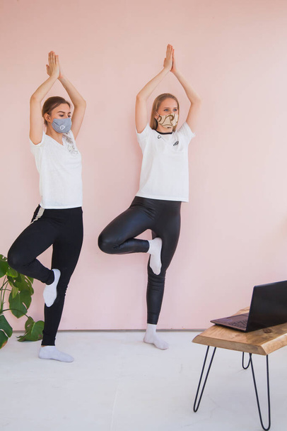 Twee zussen doen yoga thuis met laptop op quarantaine. - Foto, afbeelding